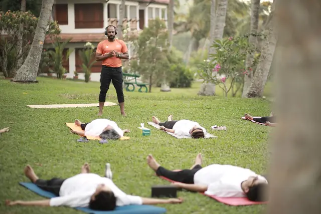 Students resting in savasana on mats laid out on the grass.