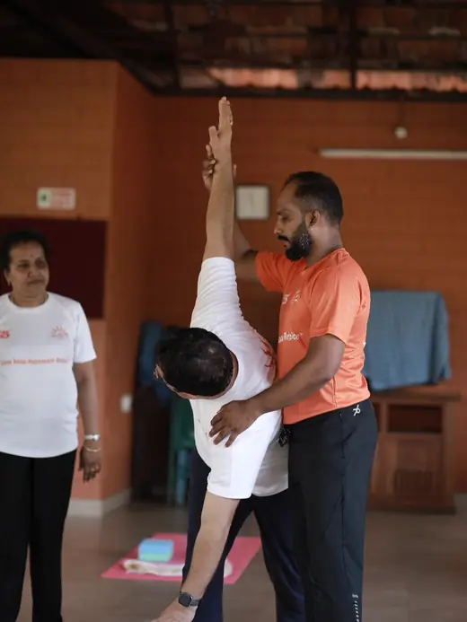 A supported shoulderstand, Abhilash steadying the student's legs.