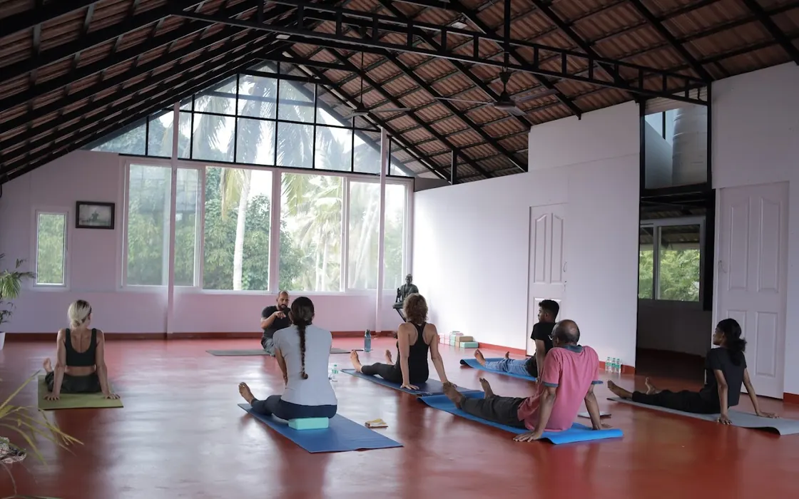 A class seated in staff pose in the tiled hall during the one-day retreat.
