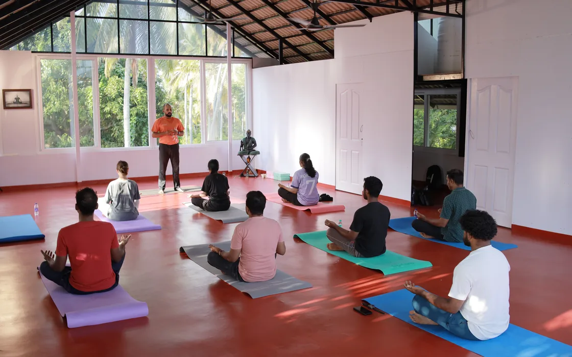 A one-day retreat class seated on mats in the shala, Abhilash teaching from the front.