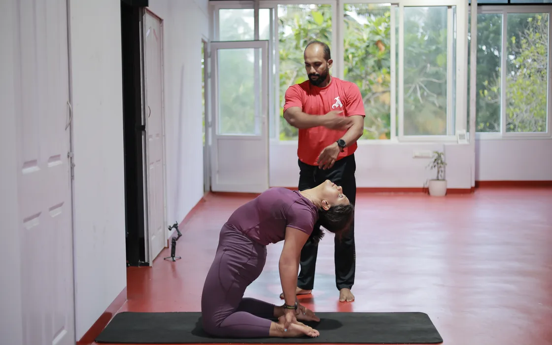 Abhilash guiding a student into camel pose in the shala.